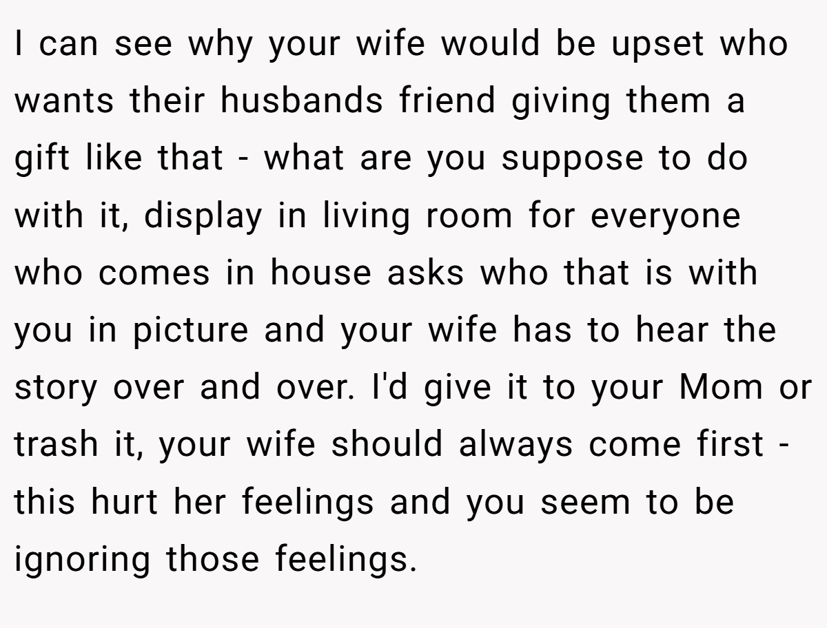 I can see why your wife would be upset who wants their husbands friend giving them a gift like that - what are you suppose to do with it, display in living room for everyone who comes in house asks who that is with you in picture and your wife has to hear the story over and over. I'd give it to your Mom or trash it, your wife should always come first - this hurt her feelings and you seem to be ignoring those feelings.