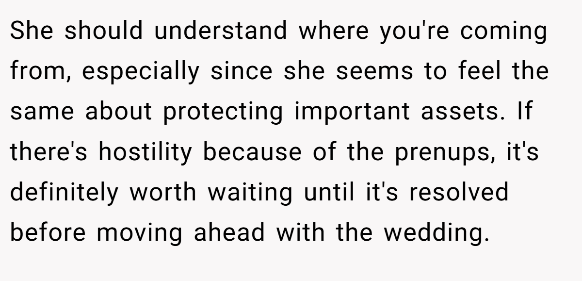 She should understand where you're coming from, especially since she seems to feel the same about protecting important assets. If there's hostility because of the prenups, it's definitely worth waiting until it's resolved before moving ahead with the wedding.