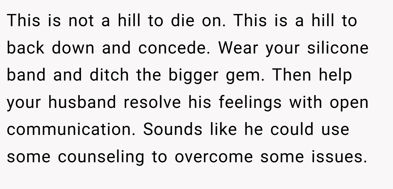 This is not a hill to die on. This is a hill to back down and concede. Wear your silicone band and ditch the bigger gem. Then help your husband resolve his feelings with open communication. Sounds like he could use some counseling to overcome some issues.