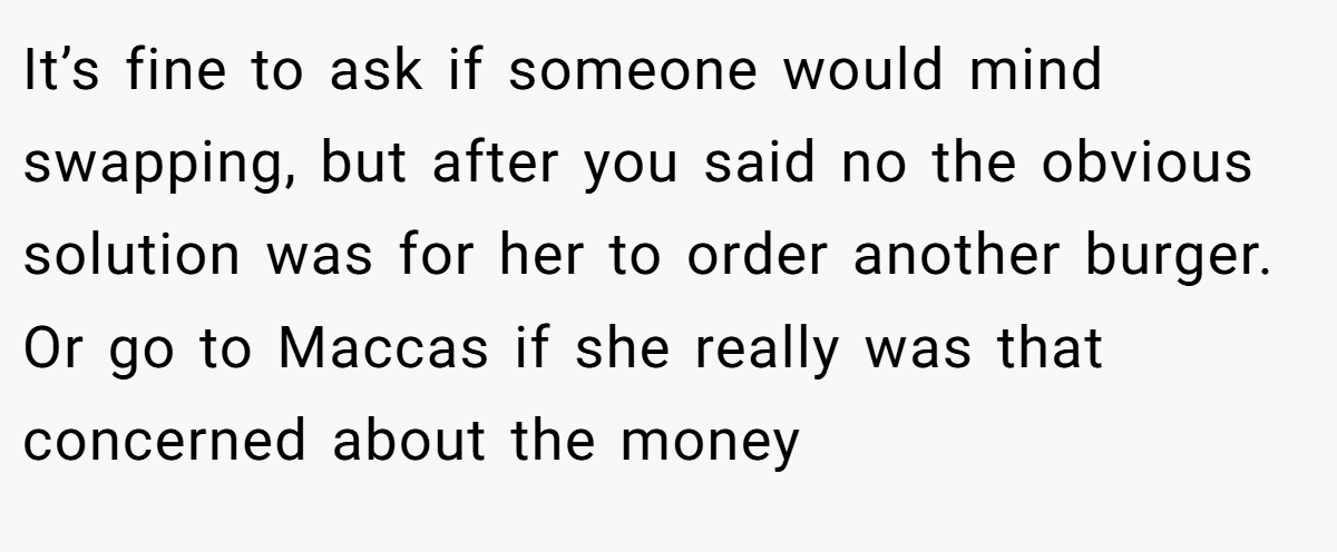 It’s fine to ask if someone would mind swapping, but after you said no the obvious solution was for her to order another burger. Or go to Maccas if she really was that concerned about the money