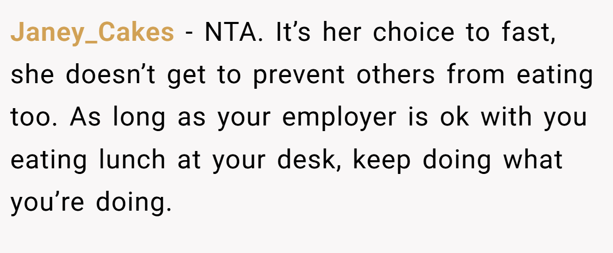 Janey_Cakes − NTA. It’s her choice to fast, she doesn’t get to prevent others from eating too. As long as your employer is ok with you eating lunch at your desk, keep doing what you’re doing.