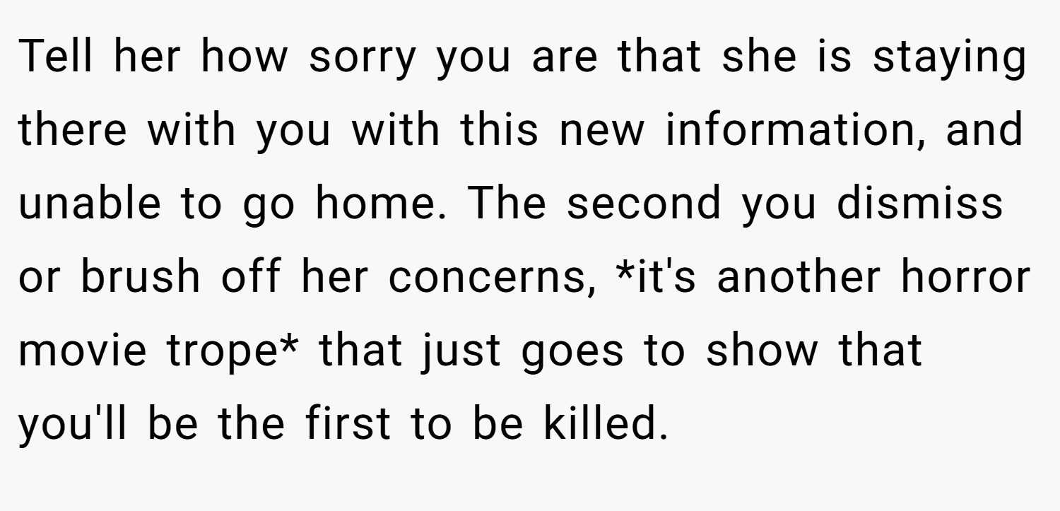 Tell her how sorry you are that she is staying there with you with this new information, and unable to go home. The second you dismiss or brush off her concerns, *it's another horror movie trope* that just goes to show that you'll be the first to be killed.
