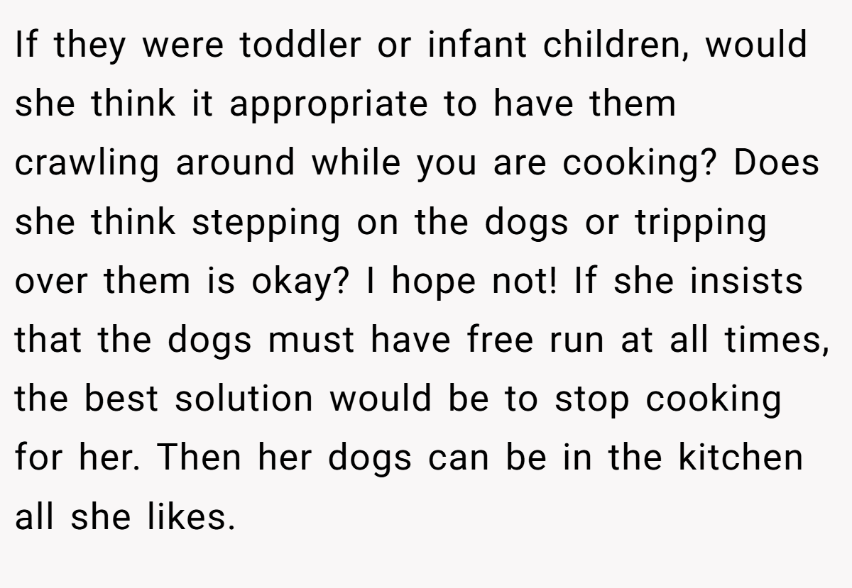 If they were toddler or infant children, would she think it appropriate to have them crawling around while you are cooking? Does she think stepping on the dogs or tripping over them is okay? I hope not! If she insists that the dogs must have free run at all times, the best solution would be to stop cooking for her. Then her dogs can be in the kitchen all she likes.