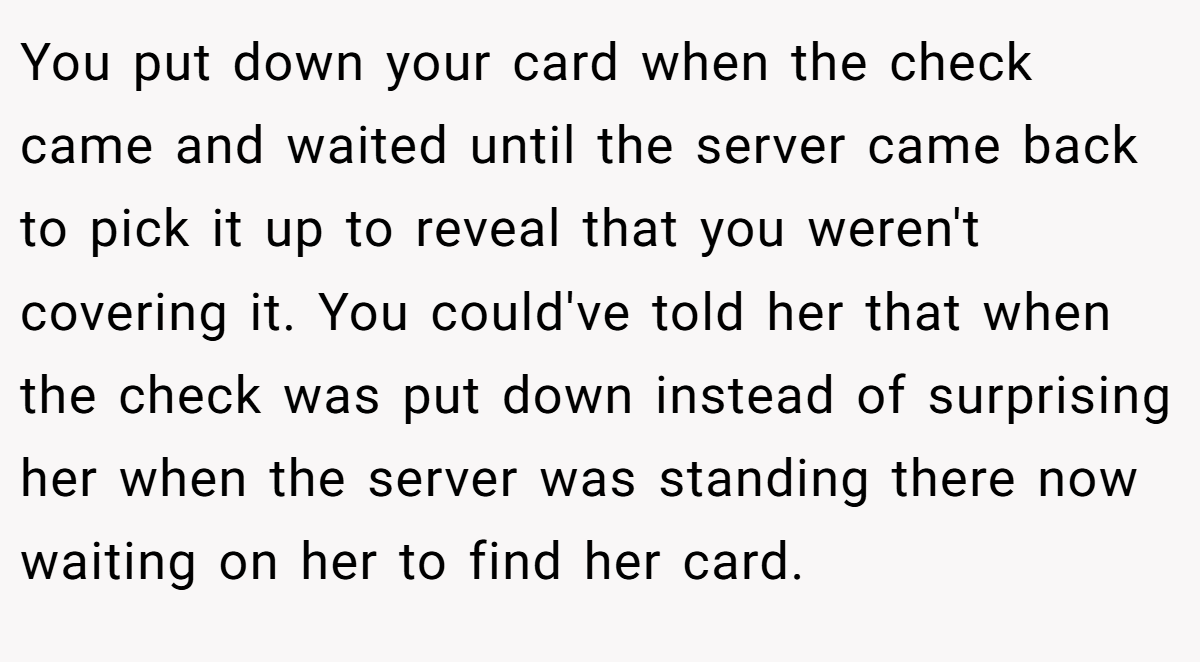 You put down your card when the check came and waited until the server came back to pick it up to reveal that you weren't covering it. You could've told her that when the check was put down instead of surprising her when the server was standing there now waiting on her to find her card.