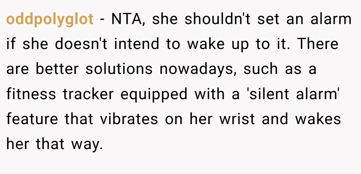 oddpolyglot - NTA, she shouldn't set an alarm if she doesn't intend to wake up to it. There are better solutions nowadays, such as a fitness tracker equipped with a 'silent alarm' feature that vibrates on her wrist and wakes her that way.