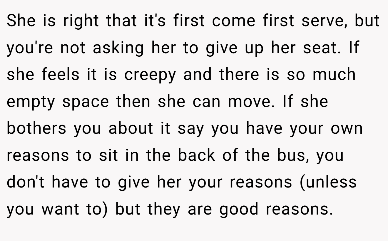 She is right that it's first come first serve, but you're not asking her to give up her seat. If she feels it is creepy and there is so much empty space then she can move. If she bothers you about it say you have your own reasons to sit in the back of the bus, you don't have to give her your reasons (unless you want to) but they are good reasons.
