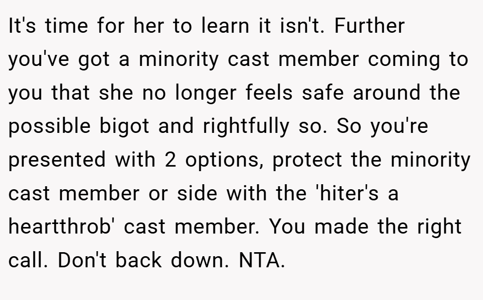 It's time for her to learn it isn't. Further you've got a minority cast member coming to you that she no longer feels safe around the possible bigot and rightfully so. So you're presented with 2 options, protect the minority cast member or side with the 'hiter's a heartthrob' cast member. You made the right call. Don't back down. NTA.
