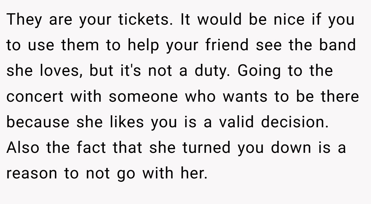 They are your tickets. It would be nice if you to use them to help your friend see the band she loves, but it's not a duty. Going to the concert with someone who wants to be there because she likes you is a valid decision. Also the fact that she turned you down is a reason to not go with her.