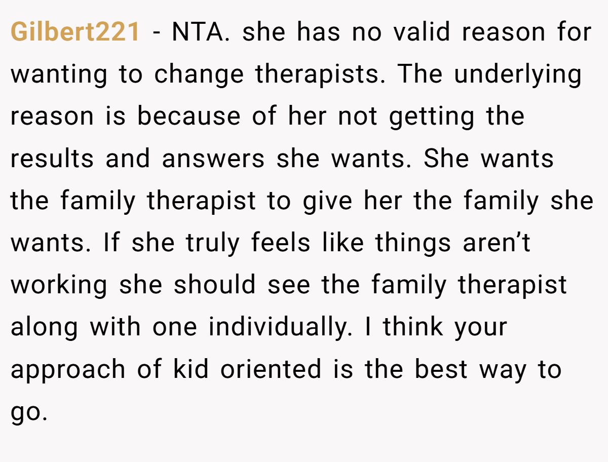 Gilbert221 − NTA. she has no valid reason for wanting to change therapists. The underlying reason is because of her not getting the results and answers she wants. She wants the family therapist to give her the family she wants. If she truly feels like things aren’t working she should see the family therapist along with one individually. I think your approach of kid oriented is the best way to go.