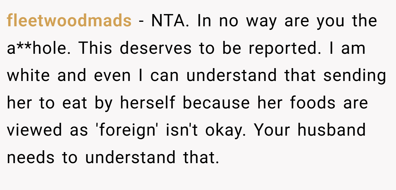fleetwoodmads − NTA. In no way are you the a**hole. This deserves to be reported. I am white and even I can understand that sending her to eat by herself because her foods are viewed as 'foreign' isn't okay. Your husband needs to understand that.