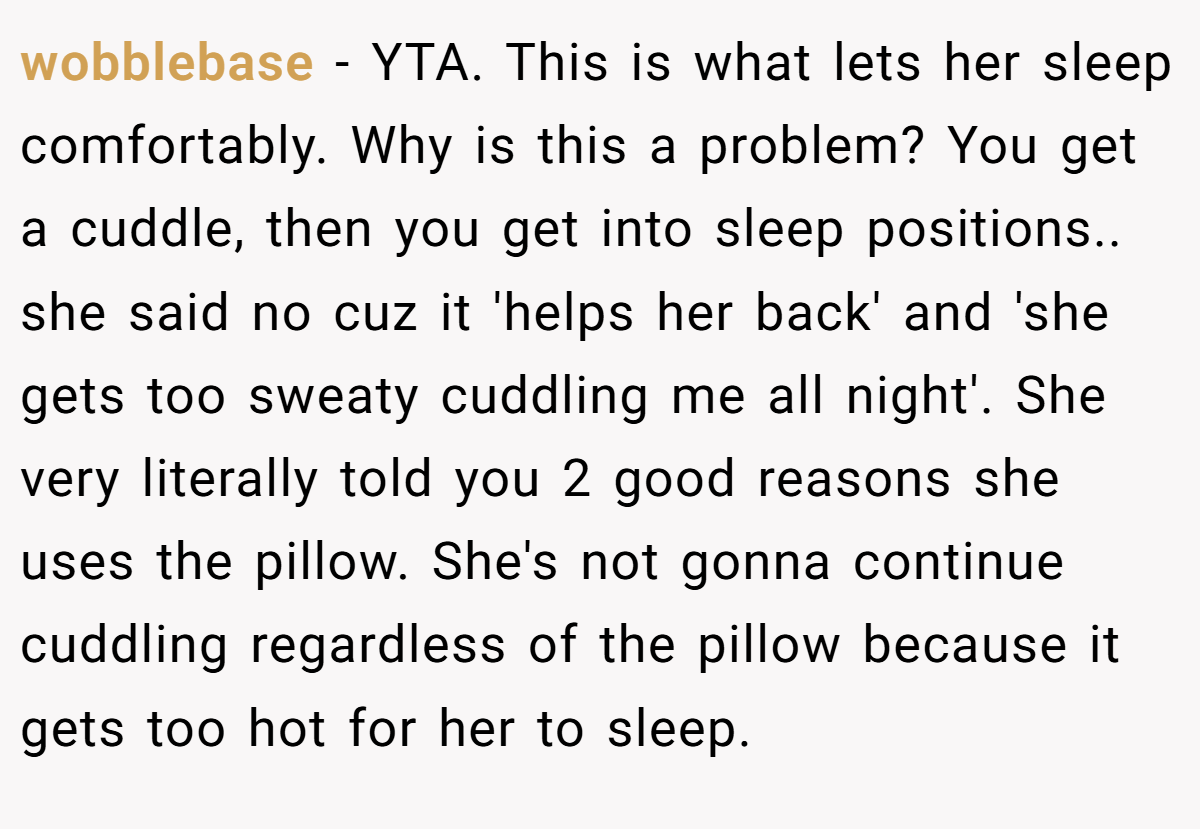 wobblebase − YTA. This is what lets her sleep comfortably. Why is this a problem? You get a cuddle, then you get into sleep positions.. she said no cuz it 'helps her back' and 'she gets too sweaty cuddling me all night'. She very literally told you 2 good reasons she uses the pillow. She's not gonna continue cuddling regardless of the pillow because it gets too hot for her to sleep.