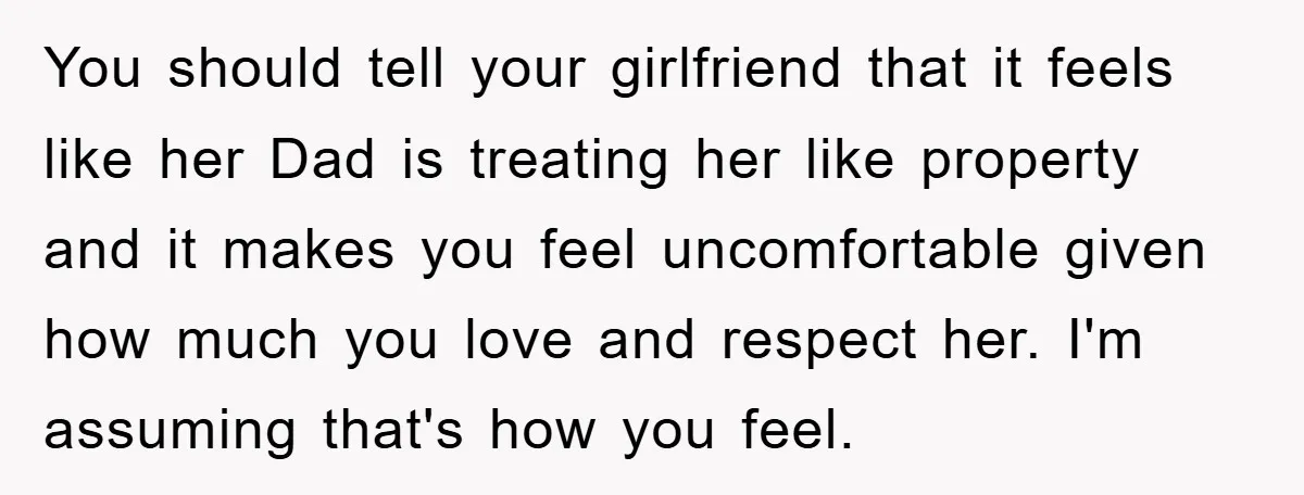You should tell your girlfriend that it feels like her Dad is treating her like property and it makes you feel uncomfortable given how much you love and respect her....