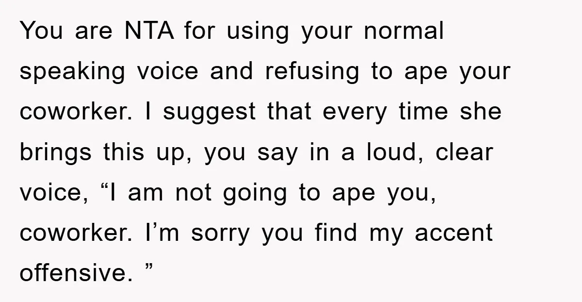 You are NTA for using your normal speaking voice and refusing to ape your coworker. I suggest that every time she brings this up, you say in a loud, clear...