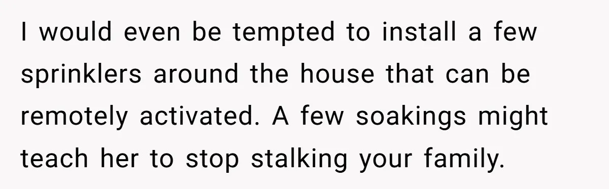 I would even be tempted to install a few sprinklers around the house that can be remotely activated. A few soakings might teach her to stop stalking your family.
