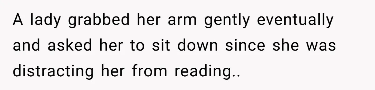 A lady grabbed her arm gently eventually and asked her to sit down since she was distracting her from reading..