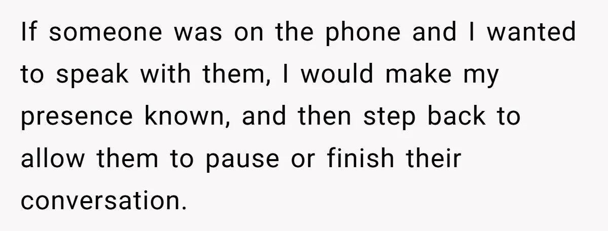 If someone was on the phone and I wanted to speak with them, I would make my presence known, and then step back to allow them to pause or finish...
