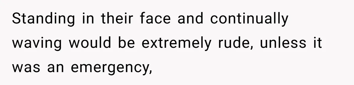 Standing in their face and continually waving would be extremely rude, unless it was an emergency,