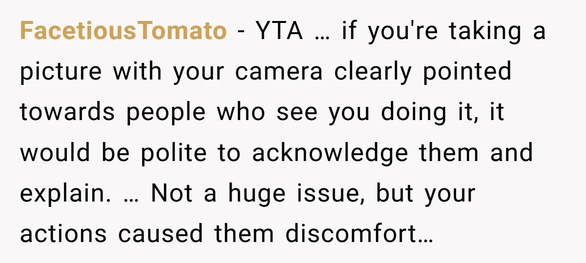 FacetiousTomato − YTA … if you're taking a picture with your camera clearly pointed towards people who see you doing it, it would be polite to acknowledge them and explain....